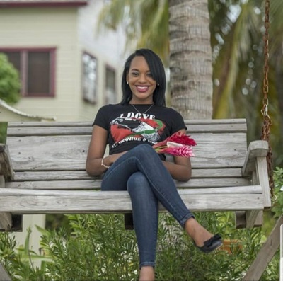 Jahnene sitting on porch swing on beach smiling with flowers in lap.