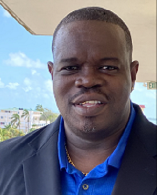 Photo of Patrick Flores dressed in a suit outdoors in tropical climate.